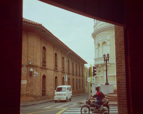 A professional taking a screen break while commuting on public transport in a vibrant Colombian city environment